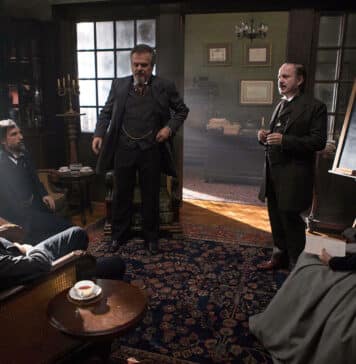 Allan Kardec hablando a cuatro personas en una sala con pizarra, mesa camilla y café, escena de época – Clase 31 Conclusión Curso de El Libro de los Espíritus